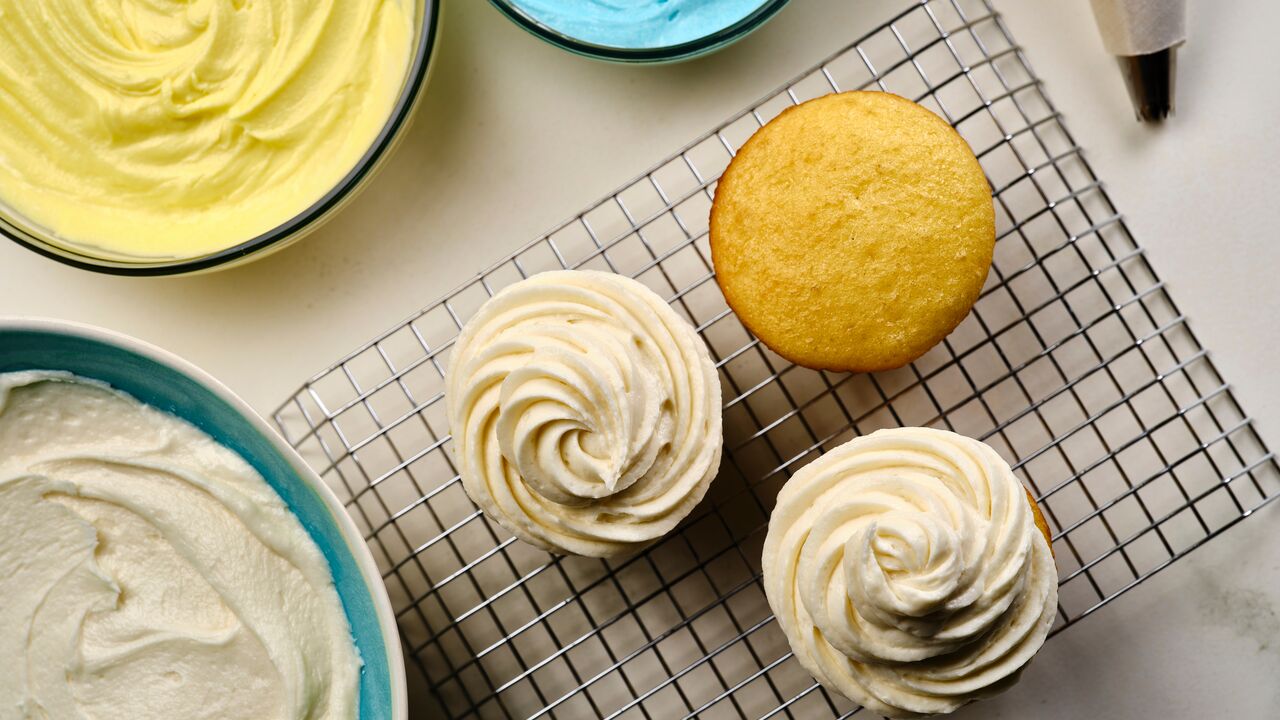piping domino sugar buttercream frosting onto vanilla cupcakes